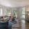 Spacious and well lit living room with wood flooring, large windows and open access to the kitchen