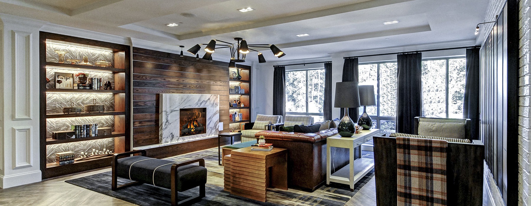 Large well lit lounge with wood floors and large windows and a fireplace